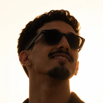 Hicham AITJAK in sunglasses, backlit by a warm sunset